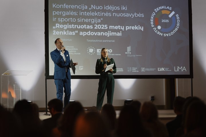 Nuotraukoje konferencijos salė su klausytojais. Tolumoje matomi renginio vedėjai ir  didelis ekranas.