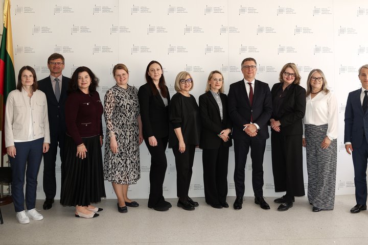 Nuotraukoje 11 susitikimo dalyvių. 3 vyrai ir 8 moterys. Už nugarų didelis stendas su Valstybinio patentų biuro besikartojančiu ženklu. Kairiame kampe stovi Lietuvos vėliava.